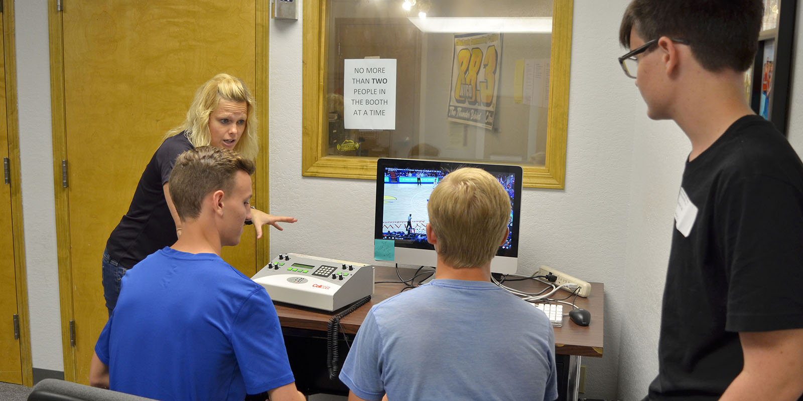 An instructor teaching students how to do play by play on the radio.